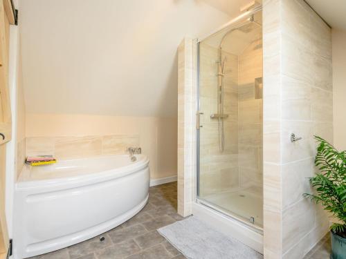 a bathroom with a shower and a white bath tub at Alder Lodge in Mattishall