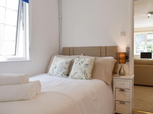 a bed with white sheets and pillows next to a window at Little Gables in Verwood