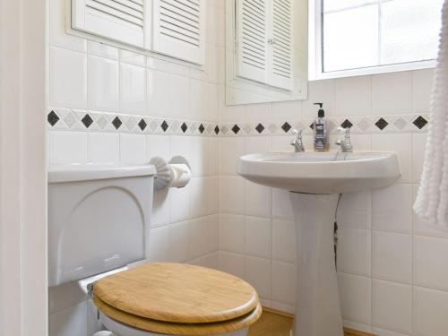 a white bathroom with a toilet and a sink at Little Gables in Verwood