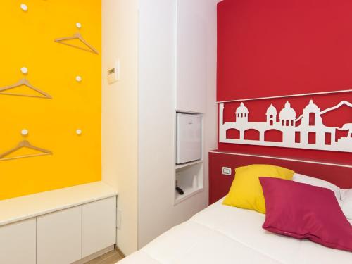 a bedroom with a bed with a red and yellow headboard at Central Rooms Il Re in Catania