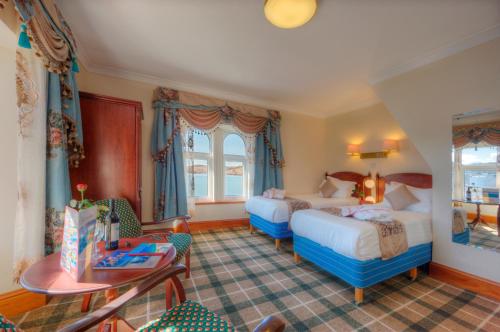 a hotel room with two beds and a table at Muthu Alexandra Hotel in Oban