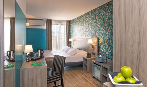 サン・ラファエルにあるUnique Hôtel & Spaのベッドとデスクが備わるホテルルームです。