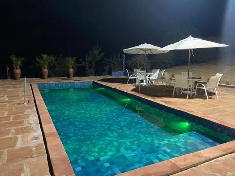 einen Pool mit Tischen, Stühlen und Sonnenschirmen in der Unterkunft Pousada Villa Paraizo in Ribeirão Claro