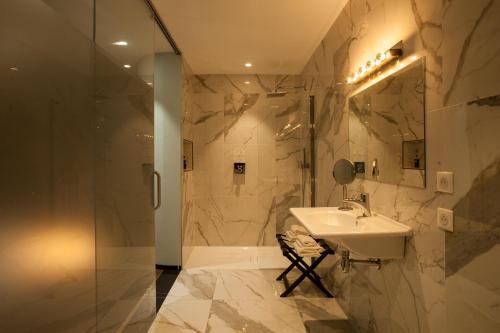 La salle de bains est pourvue d'un lavabo et d'une douche. dans l'établissement Hotel La Pietra Restaurant & Spa, à LʼÎle-Rousse