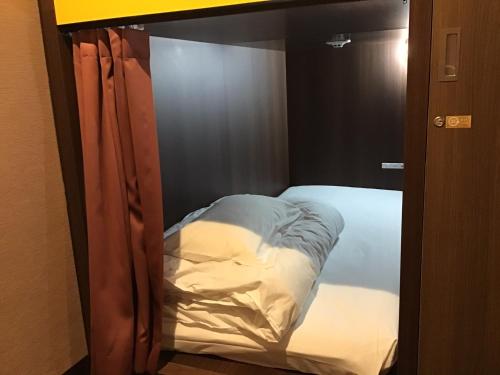 a small bed in a room with a glass door at ゲストハウス長岡街宿 in Nagaoka