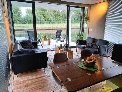 uma sala de estar com mesa e cadeiras em AquaHome - NP de Biesbosch - Bijzonder overnachten op een houseboat! em Werkendam