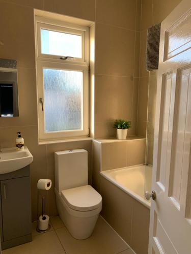 La salle de bains est pourvue de toilettes, d'une baignoire et d'une fenêtre. dans l'établissement 4 bedroom House nr Cardiff City Centre, à Cardiff