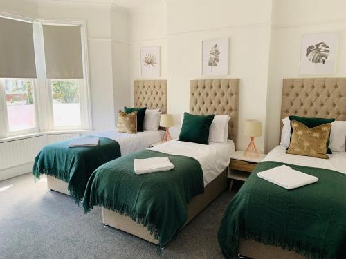 - une chambre avec 2 lits avec des couvertures vertes et des fenêtres dans l'établissement 4 bedroom House nr Cardiff City Centre, à Cardiff