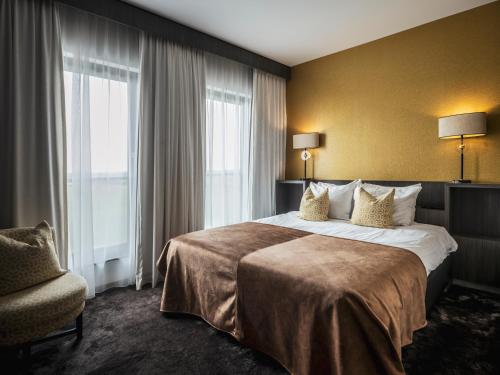 een hotelkamer met een groot bed en een stoel bij Van der Valk Hotel Hoorn in Hoorn