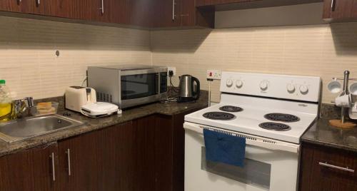 a kitchen with a white stove and a microwave at King Abdullah Economic City Apartment - KAEC شقة بمدينة الملك عبدالله الاقتصادية- حي الواحة in King Abdullah Economic City