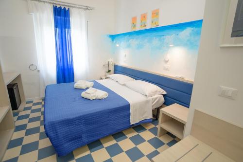 una camera da letto con un letto blu e asciugamani di EDEN CONERO Camere Numana Centro a Numana