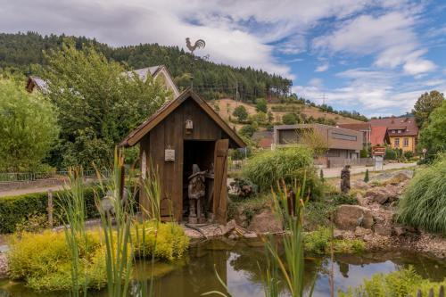 a small shed in a garden next to a pond at Mosers Blume Relax & Genuss Hotel in Haslach im Kinzigtal