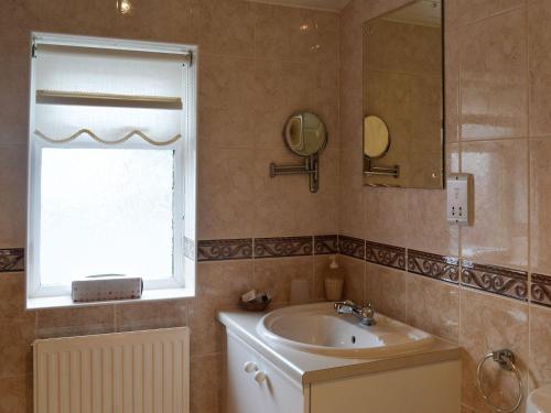 a bathroom with a sink and a mirror and a window at West Tannacrieff in Stewarton