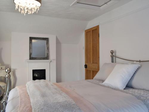 a white bedroom with a bed and a chandelier at Wilma Cottage in Geldeston
