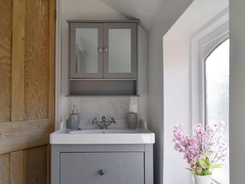 a bathroom with a white sink and a mirror at Wilma Cottage in Geldeston