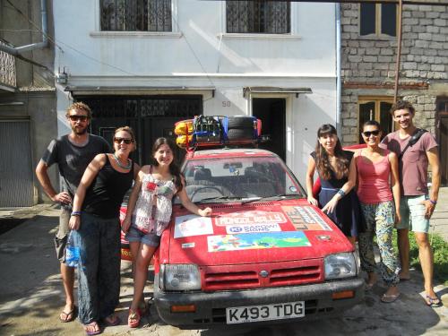 a group of people standing next to a red car at Nitsa Guest House in Gori