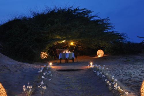 a table on the beach at night with lights at Laya Safari Resorts & Spa in Yala