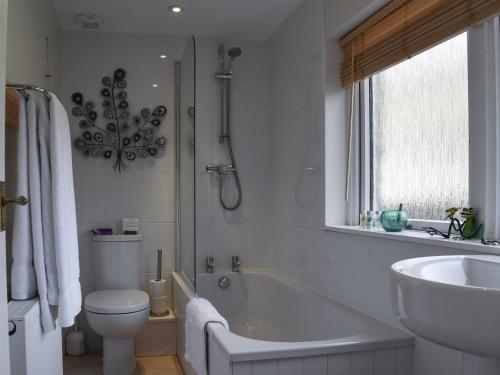 a bathroom with a tub and a toilet and a sink at Lochearnside Lodge in Saint Fillans