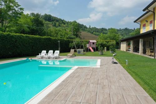 einen Pool mit zwei Stühlen und ein Haus in der Unterkunft App in Villa con Piscina - 45 min Venezia - Zona Unesco in San Pietro di Feletto