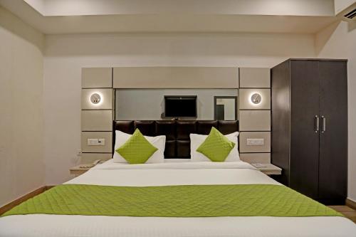 1 dormitorio con 1 cama blanca grande con almohadas verdes en Hotel Royal Saffron - Kirti Nagar en Nueva Delhi