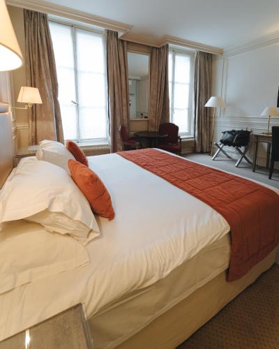a hotel room with a large bed with orange pillows at Hotel de L'Universite in Paris