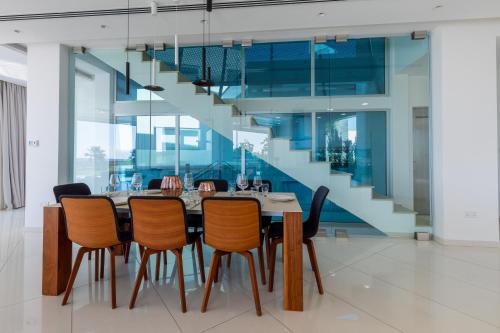 a dining room with a table and chairs and a staircase at Beachfront Luxury Villa Glory in Ayia Napa