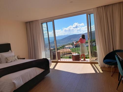 kobieta patrząca przez okno pokoju hotelowego w obiekcie Quinta Manhas Douro w mieście Provesende