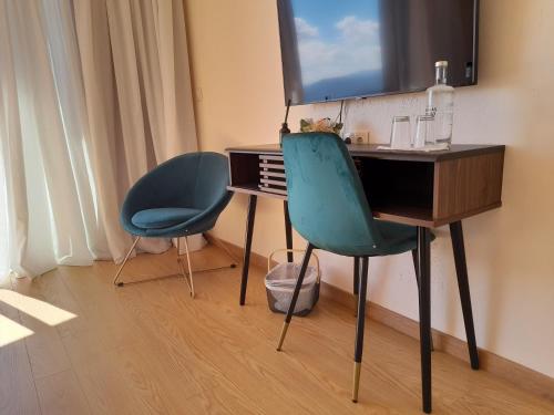 a desk and two chairs in a room with a television at Quinta Manhas Douro in Provesende