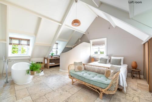 a attic bedroom with a bed and a bath tub at Boutique hotel Villa Oldenhoff in Abcoude