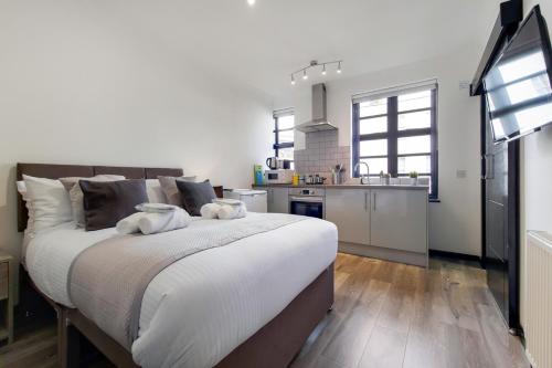 a bedroom with a large bed and a kitchen at Langdon Brooks Apartments in London