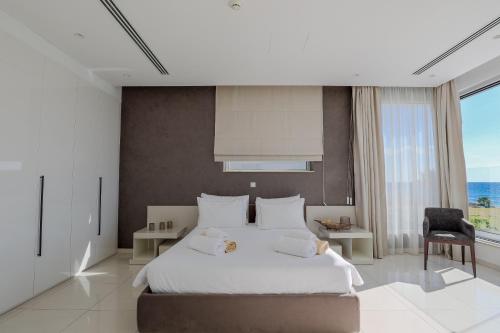 a bedroom with a white bed and a large window at Beachfront Luxury Villa Glory in Ayia Napa