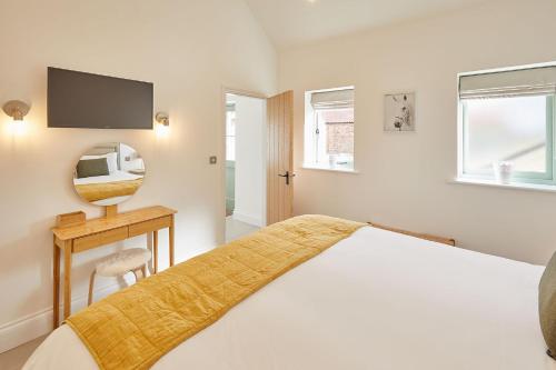 a white bedroom with a bed and a mirror at The Stables Cottage in Yedingham