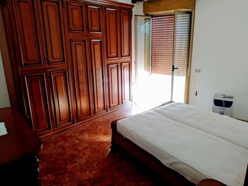 1 dormitorio con 1 cama y armarios de madera en Casa Centineo en Barcellona-Pozzo di Gotto