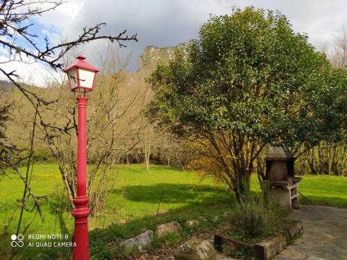 a red lamp post in a park with a tree at Araiztar in Irañeta