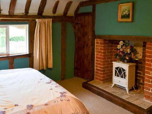 a bedroom with a bed and a brick fireplace at Tattlepot Farmhouse in Tivetshall Saint Margaret