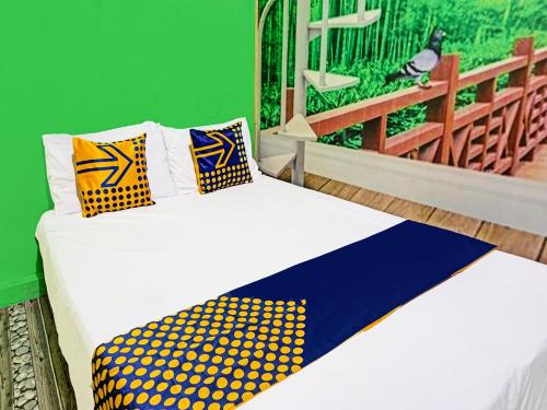 uma cama com almofadas amarelas e azuis e uma parede verde em OYO 91697 Nyaman Homestay Syariah em Pare