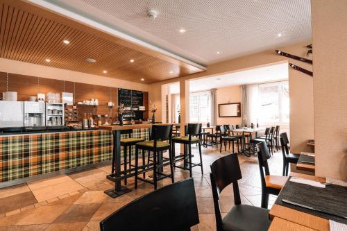 a restaurant with a bar with chairs and tables at Hotel Les Amis in Saas-Fee
