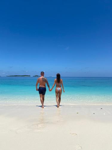 a man and a woman walking on the beach at Koimala Hotel in Maamigili