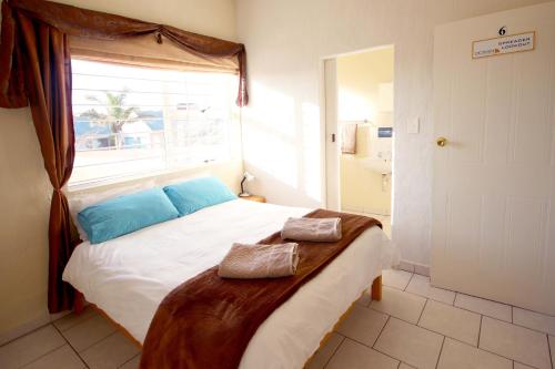 a bedroom with a bed with blue pillows and a window at Ocean House Holiday Accommodation in Langebaan