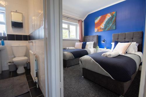 1 dormitorio con 2 camas, aseo y paredes azules en Stunning House Free Parking Garden WiFi en Bristol