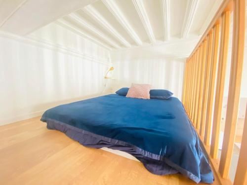 Coeur de ville, appartement moderne avec mezzanine في لاوون: غرفة نوم بسرير ازرق في غرفة بيضاء