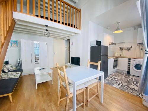 eine Küche und ein Wohnzimmer mit einem weißen Tisch und Stühlen in der Unterkunft Coeur de ville, appartement moderne avec mezzanine in Laon