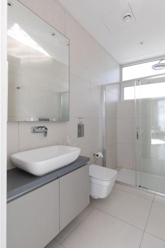 a white bathroom with a sink and a toilet at Beachfront Luxury Villa Glory in Ayia Napa