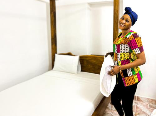 una mujer está de pie junto a una cama en Shoki Shoki Hostel en Zanzíbar