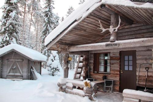 ein Blockhaus im Schnee mit einem Tisch in der Unterkunft Kopistus in Syöte