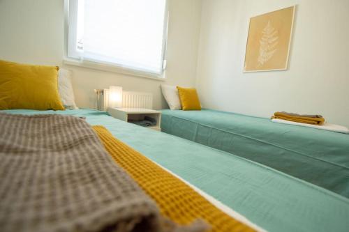 Habitación con 2 camas azules y ventana. en WHITE FIELDS-Central 2-bdrm apartment with parking, en Novi Sad