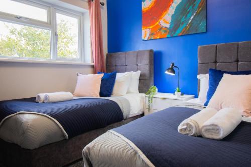 three beds in a room with blue walls at Stunning House Free Parking Garden WiFi in Bristol