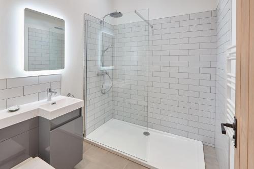 a white bathroom with a shower and a sink at Rose Cottage in Yedingham