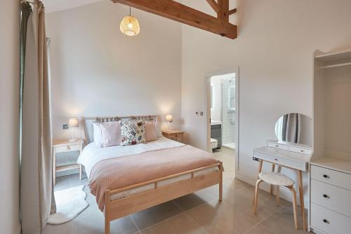 a white bedroom with a bed and a mirror at Rose Cottage in Yedingham