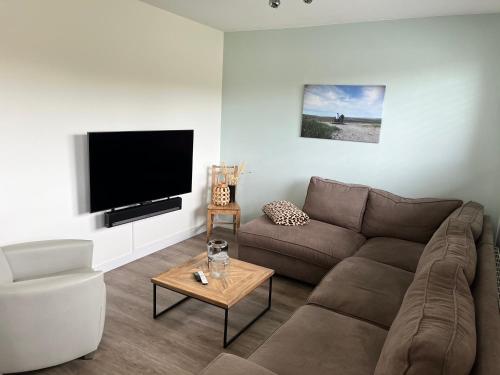 a living room with a couch and a flat screen tv at Parnassia in De Koog